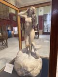 A statue of Aphrodite standing on a dolphin, on museum display